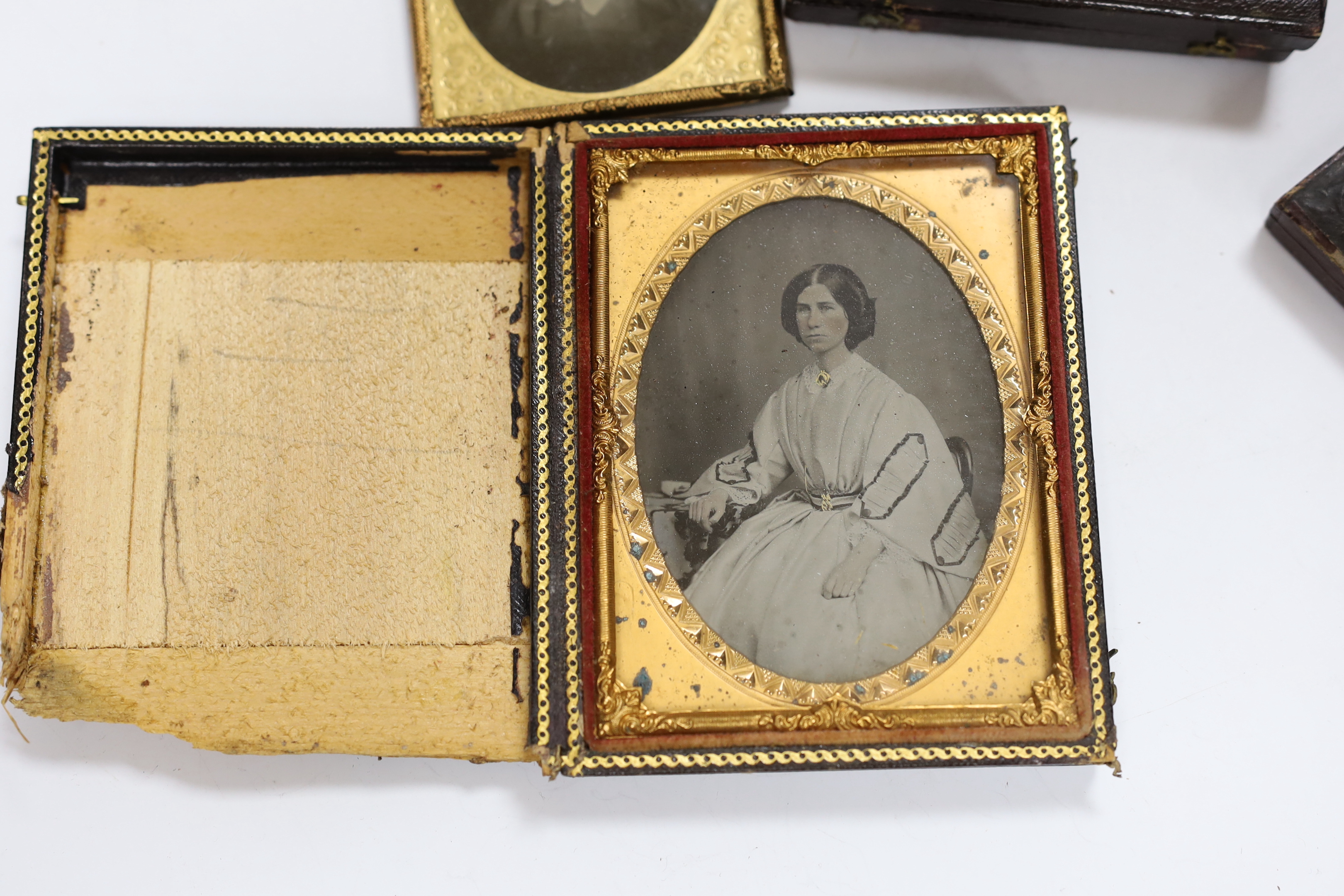 A collection of mid 19th century ambrotype portrait photographs, all mounted in brass etc frames, some in decorative cases, two examples framed (25)
